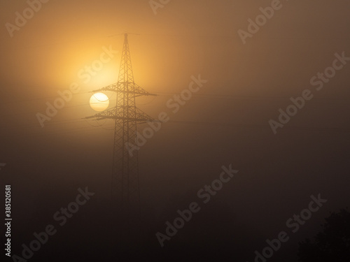 foggy landscape with a big power pole in the sunrise