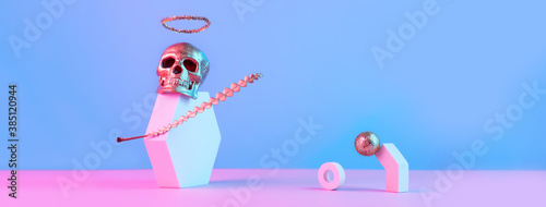 Golden skull with halo and geometric shapes on a pink blue background, Halloween concept.