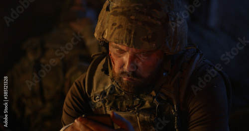 Depressed soldier drinking near fire at night