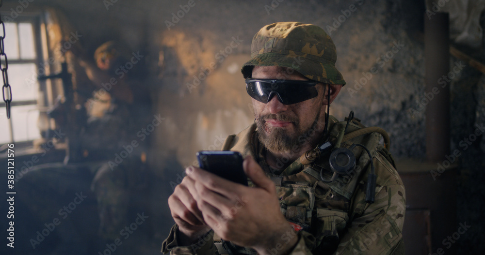 Military man using smartphone inside grungy building Military man using smartphone inside grungy building