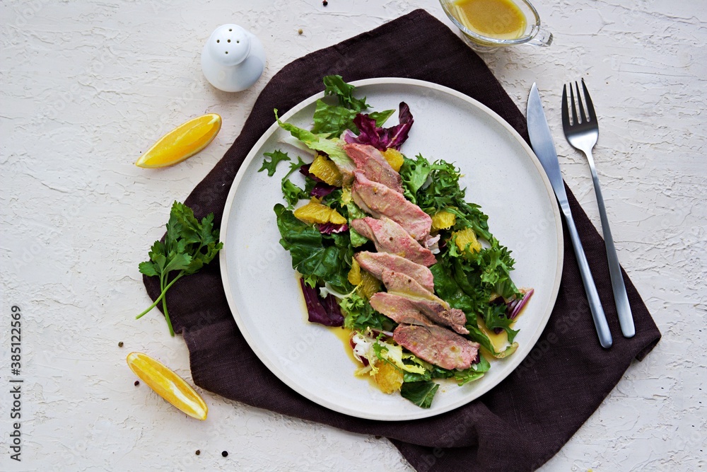 Warm salad with a mixture of salad leaves, baked duck and orange on a clay plate Warm salad with a mixture of salad leaves, baked duck and orange on a clay plate