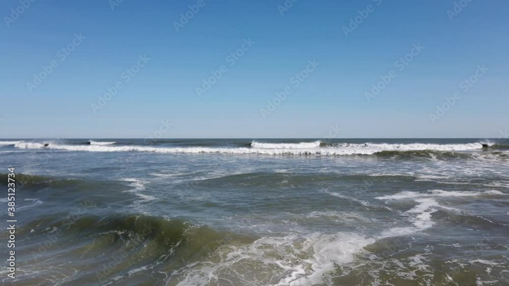 Dark rough ocean with waves forming and breaking one after the other leaving white foam Dark rough ocean with waves forming and breaking one after the other leaving white foam