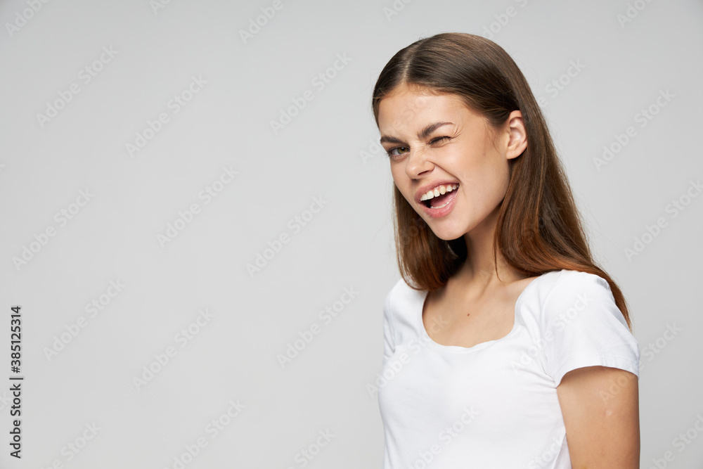 Cheerful woman winks smile white t-shirt cropped views light background Cheerful woman winks smile white t-shirt cropped views light background