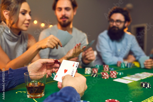 Cuadro en lienzo Man holding a chip and pair of aces while playing poker with his friends on casi