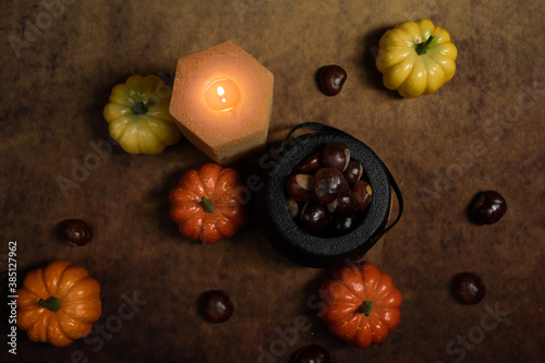 Top view of still life of autumn decorations with pumpkins, cauldrons, chestnuts and candle