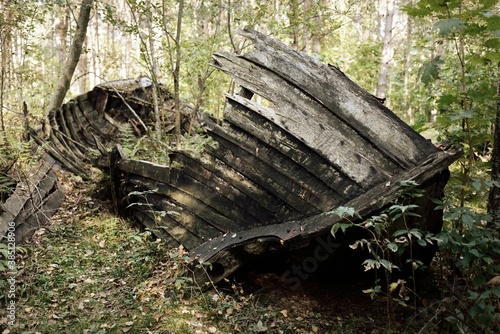 Old abandoned wooden fishing boat in the forest, close-up. Boats cemetery in Mazirbe, Livonian village, Latvia. Concept image, atmospheric landscape, travel destinations, shipwreck, past, history photo