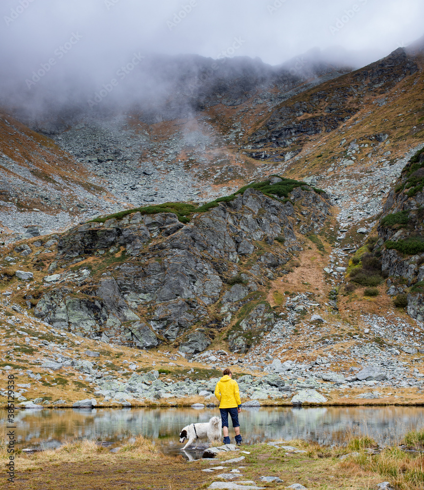woman and dog trekking in high mountains