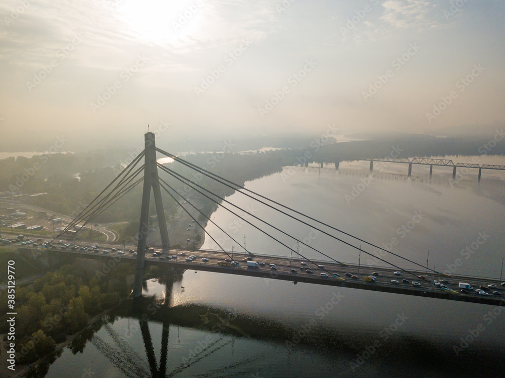 Aerial drone view. North bridge in Kiev in the rays of a sunny morning. Autumn haze in the air, cars are driving across the bridge. Aerial drone view. North bridge in Kiev in the rays of a sunny morning. Autumn haze in the air, cars are driving across the bridge.