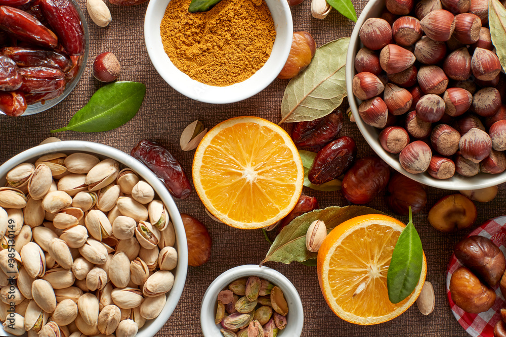 Various raw nuts: hazelnuts, pistachios, chestnuts, dates and oranges. Various raw nuts: hazelnuts, pistachios, chestnuts, dates and oranges.