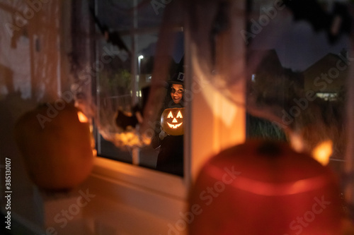 Woman witch carrying a pumpkin for Halloween night - Spooky scene with halloween symbols and signs - holidays, culture and lifestyle in UK and United States