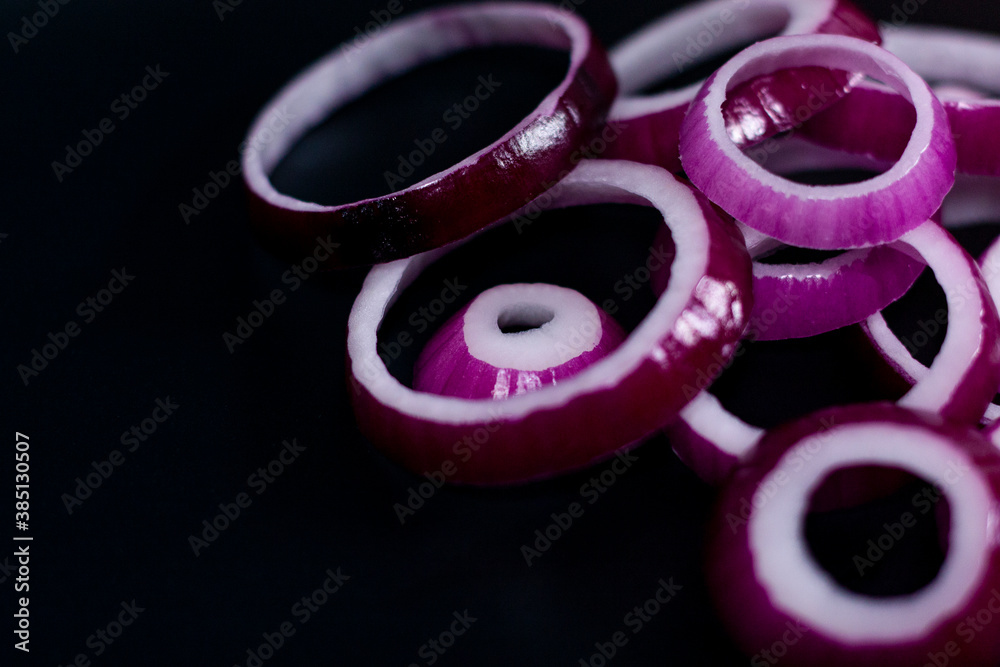 Sliced red onion on a dark background. Location in the form of a mound in the upper right corner. Sliced red onion on a dark background. Location in the form of a mound in the upper right corner.
