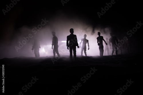 Scary view of zombies at cemetery dead tree, moon, church and spooky cloudy sky with fog, Horror Halloween concept with glowing pumpkin. Selective focus