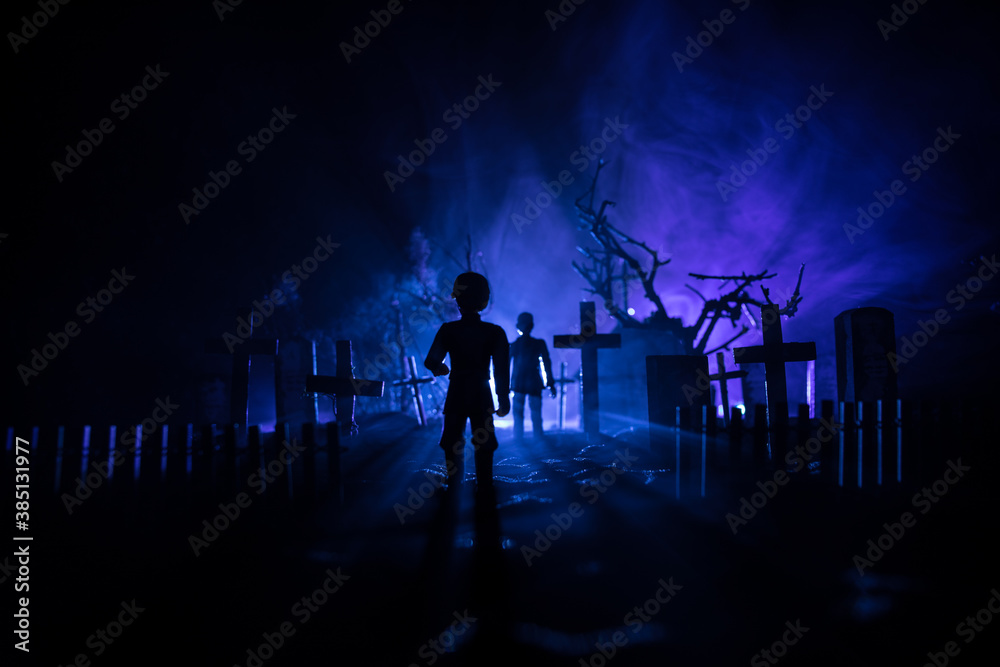 Girl walking alone in the cemetery at night. Dark toned foggy background. Horror Halloween concept