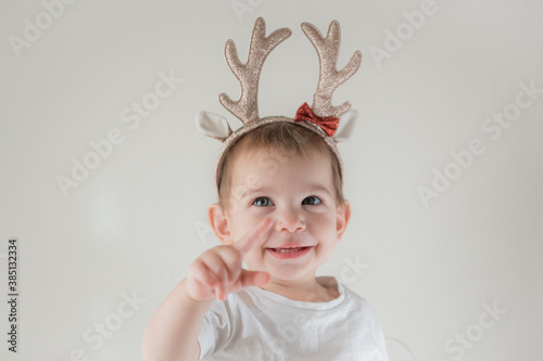 Little infant girl with shiny glitter rain deer horns costume. New year and christmas party celebration. Christmas holidays.