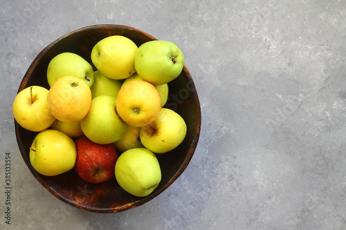 Fresh organic ripe apples in a bowl on a grey background  top view. Copy space