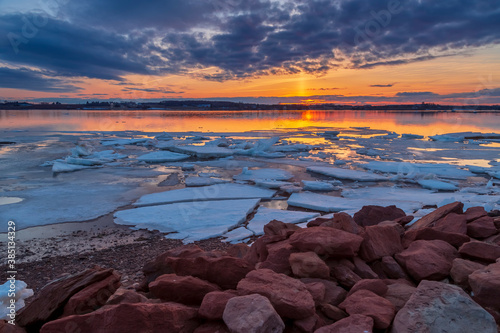 Vibrant and serene winter landscape with a single frozen ice sheet floating on a lake during a late sunset in Charlottetown, Prince Edward Island, Canada. photo