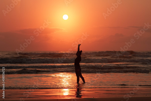 a silhouette of young beautiful girl looking to a perfect sunrise in the background 