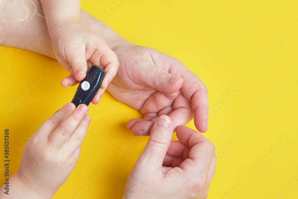 Fototapeta premium grandmother is doing glucose level finger blood test to child