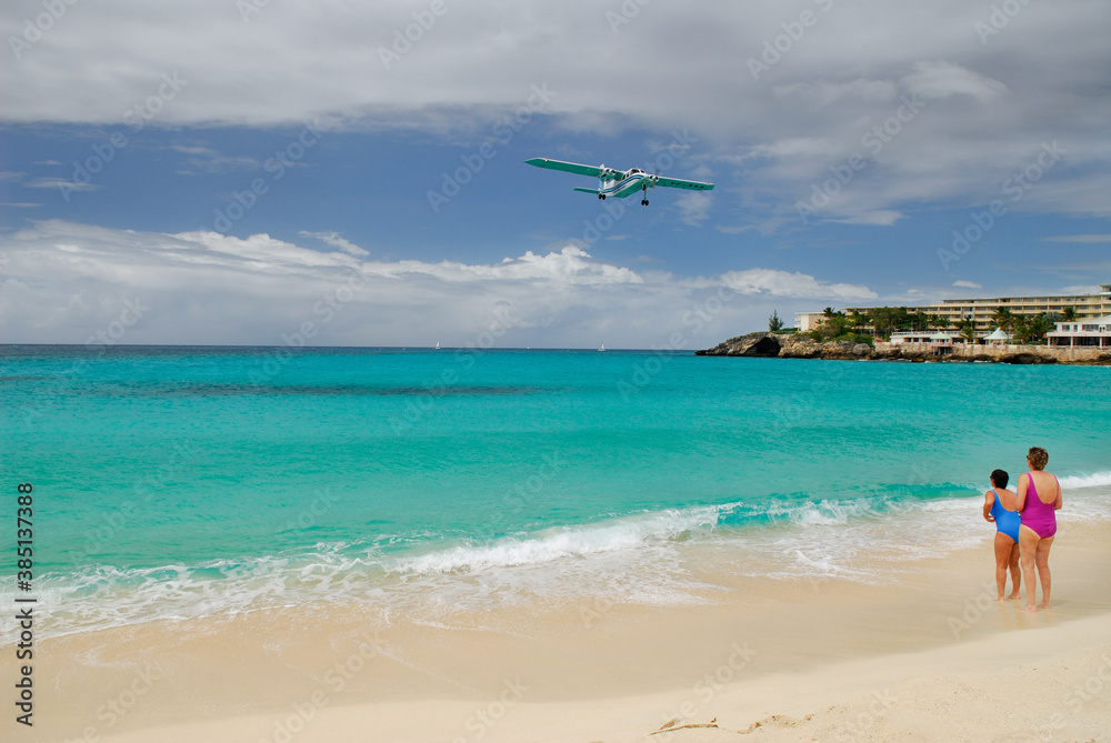 Two female beachgoers watch a plane land in St Maarten