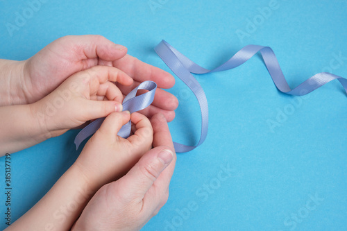 grandmother and granddaughter hold a blue ribbon on a blue background, photo