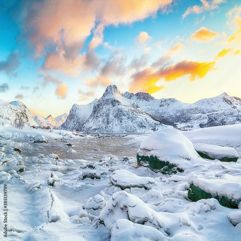 Obraz premium Picturesque frozen Flakstadpollen and Boosen fjords with cracks on ice during sunrise with Hustinden mountain on background on Flakstadoya island