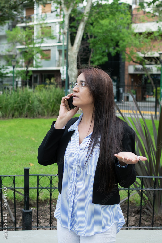Latin business woman discussing on cellphone about work in the park Latin business woman discussing on cellphone about work in the park