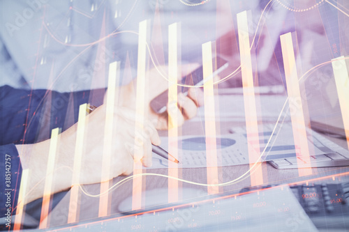 Double exposure of man's hands holding and using a digital device and forex graph drawing. Financial market concept.