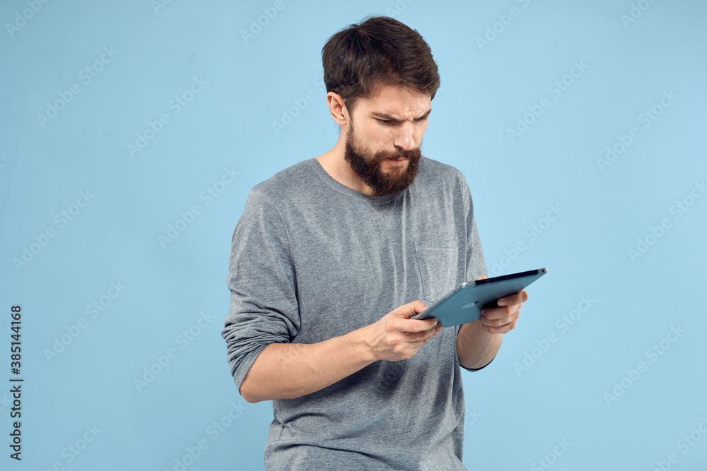 Emotional man with a tablet in the hands of a wireless device internet technology lifestyle blue background