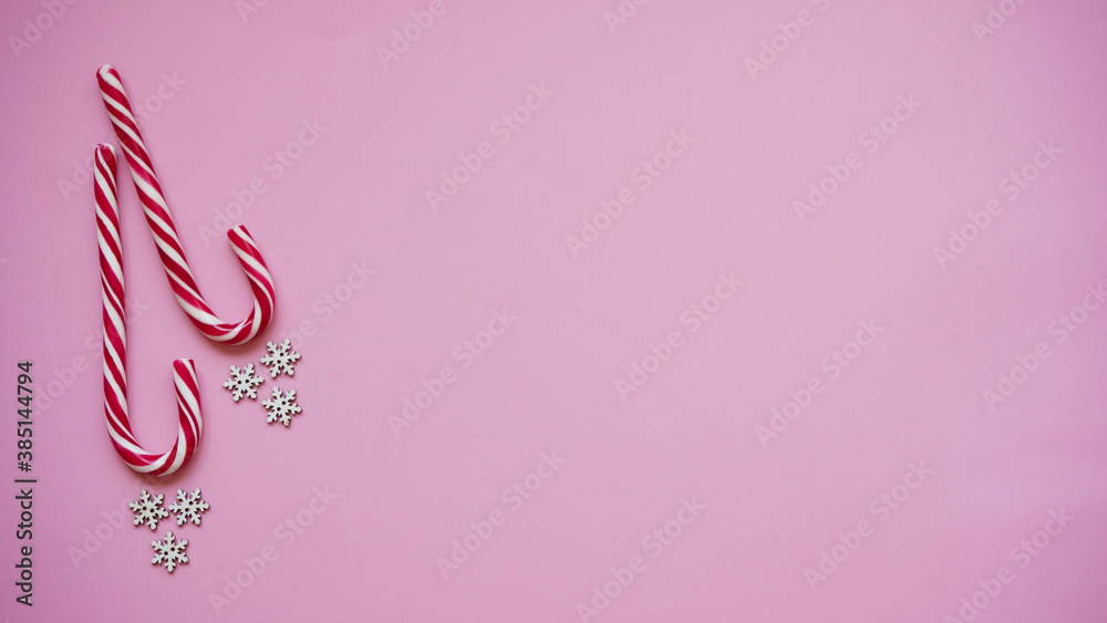 Christmas lollipop and white snowflakes pink background, copy space, top view, flat lay.Christmas and New Year decor concept