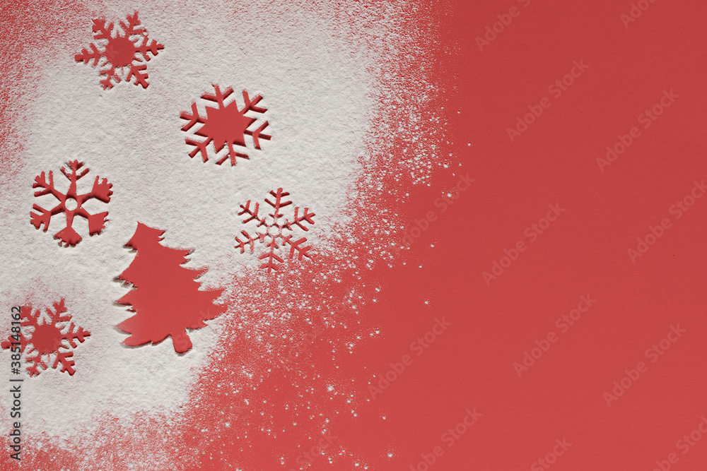 The outline of a Christmas tree and snowflakes on spilled flour. Red