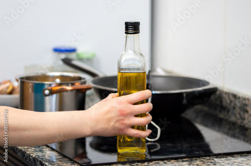 close up hand of a woman holding a glass bottle of olive oil