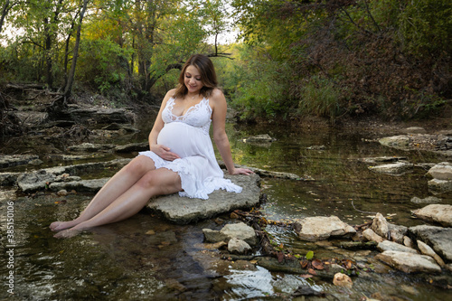 Fotografija Pregnant expecting young mother sitting on rock on the water creek looking down