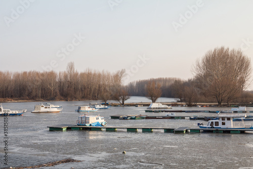 Panorama of the port of Kovin, on the Danube, with boats and ship anchored in frozen waters in winter. Kovin is a city of Vojvodina province, in the district of Banat