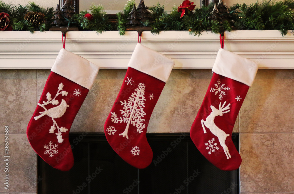 Fotografie Three red christmas stockings on fireplace mantle