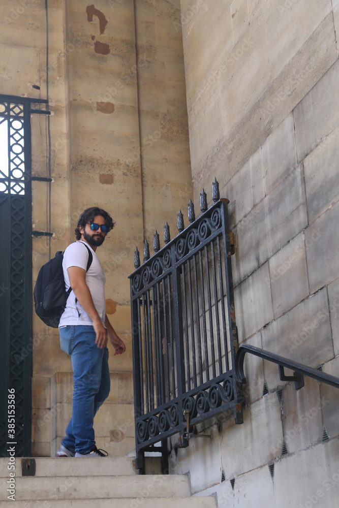 Vertical shot of an attractive Brazilian male tourist with sunglasses in a french museum.