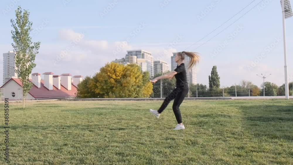 Beautiful girl is doing exercises in the fresh air. Against the background of the city. Gymnastics, acrobatics. Training on green grass. Slow motion. Shot in 4k Beautiful girl is doing exercises in the fresh air. Against the background of the city. Gymnastics, acrobatics. Training on green grass. Slow motion. Shot in 4k
