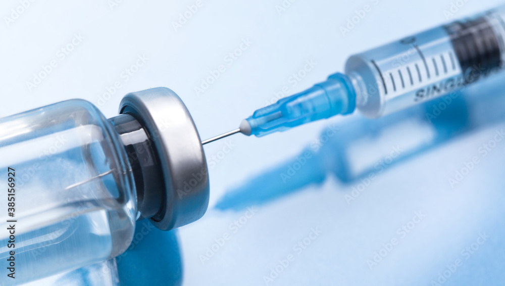 Medical syringe with a needle and a bollte with vaccine.