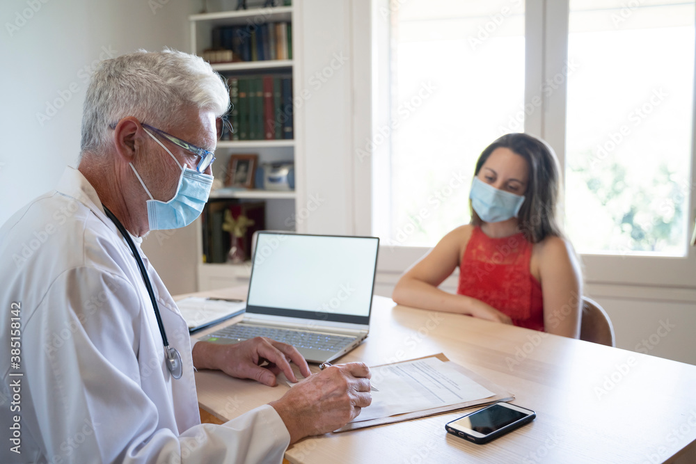Doctor examining medical record of patient while sitting in clinic