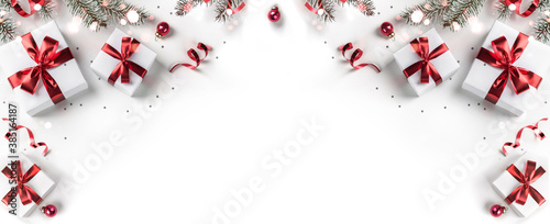 Creative frame made of Christmas fir branches, gift boxes, red decoration, sparkles and confetti on white background. Xmas and New Year holiday, bokeh, light. Flat lay, top view photo