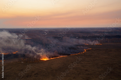 Dangerous wildfire going to meadow under sunset sky
