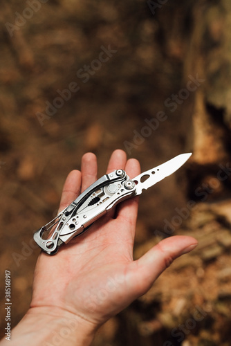 Close-up of male hiker's hand with penknife in forest