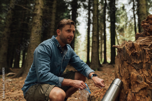 Male biologist looking away while taking samples in forest photo