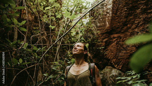 Woman trekking in forest between rock and trees photo