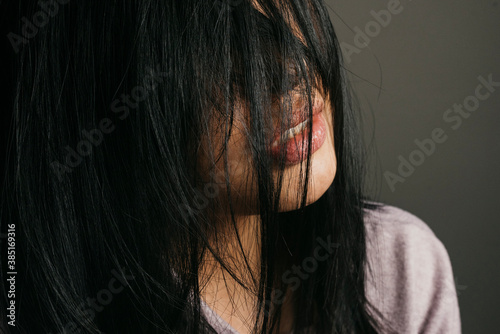 Close-up of woman with messy black hair against wall
