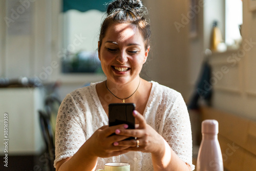 Close-up of smiling voluptuous woman using mobile phone while sitting in restaurant photo