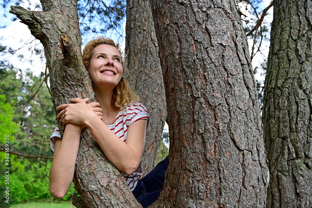 © Anne Jensen/Westend61 - Thoughtful woman embracing while sitting on tree in forest © Anne Jensen/Westend61 - Thoughtful woman embracing while sitting on tree in forest