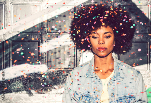 Confetti falling on thoughtful woman looking down while standing against wall photo