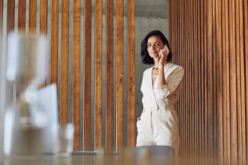 Female entrepreneur talking over mobile phone while standing at entrance in office
