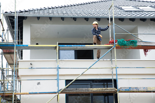 Construction worker standing on scaffold at construction site photo