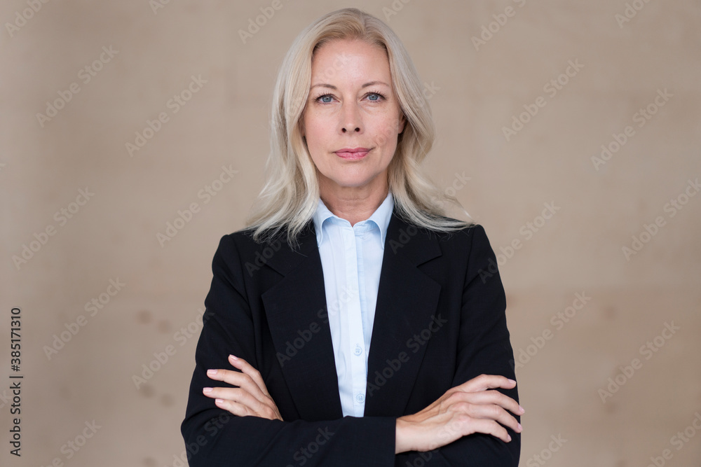 Confident female entrepreneur with arms crossed standing against wall in office Confident female entrepreneur with arms crossed standing against wall in office